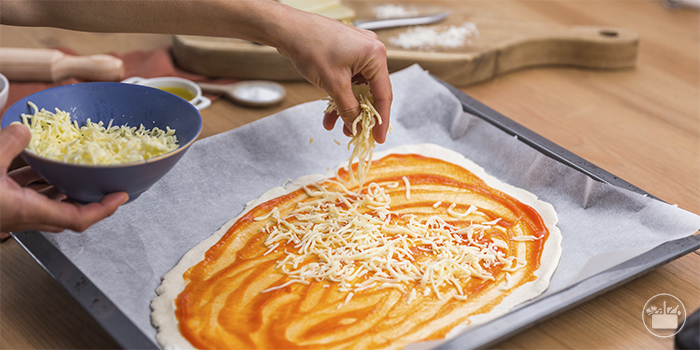 Untar a base da pizza com o tomate frito e polvilhar generosamente com a mozarela. 