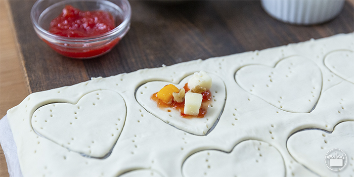 Fazer mais 8 cortes em forma de coração. Em 4 deles, colocar doce de tomate, cubos de queijo e nozes.